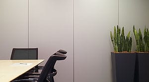 Mobiele akoestische wanden in een modern kantoor met vergadertafel en zwarte stoelen