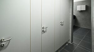 Sanitaire toiletcabines met lichtgrijze wandpanelen en RVS handgrepen in een professionele omgeving